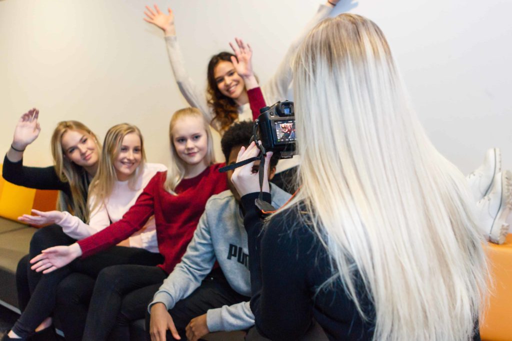 Nuori ottaa kuvaa ryhmästä hymyileviä nuoria.